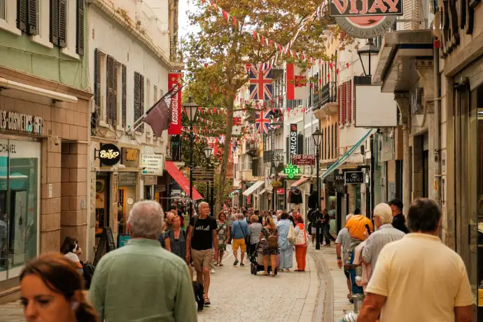People walking down a street lined with shops and flags